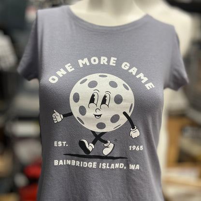 A gray women's t-shirt with a graphic print of a pickleball character and the text 'ONE MORE GAME Bainbridge Island, WA'.